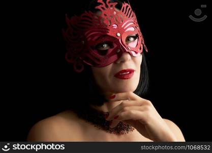 beautiful adult woman of Caucasian appearance with black hair wearing a red shiny carnival mask, lips parted and painted with red lipstick, dark background