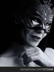 beautiful adult woman of Caucasian appearance with black hair wearing a shiny carnival mask, black and white tinting
