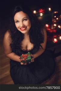 Beautiful adult woman wearing black dress and she holds a christmas gift