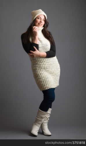 Beautiful adult woman wearing knitted wear, gray background