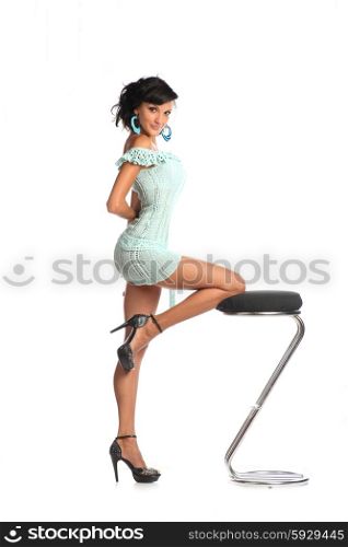 Beautiful adult woman with fashion hairstyle poses at studio on bar stool .