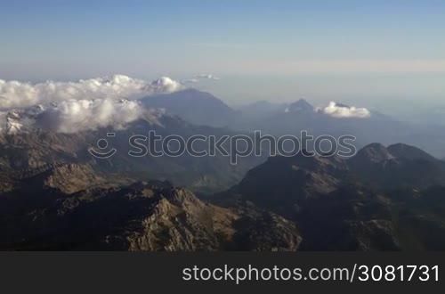 Beautiful aerial scenery with mountain range and clouds. Observing nature landscape from flying airplane