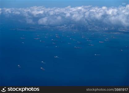 Beautiful aerial view above the clouds, below is the bay, with many cargo boats near Changi Airport, Singapore. Soft focus.. Beautiful aerial view above clouds.
