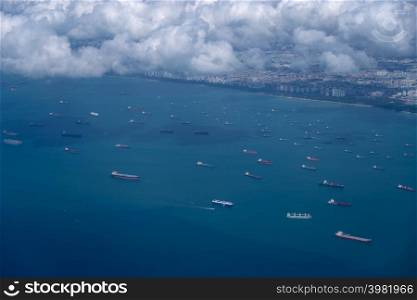Beautiful aerial view above the clouds, below is the bay, with many cargo boats near Changi Airport, Singapore. Soft focus.. Beautiful aerial view above clouds.