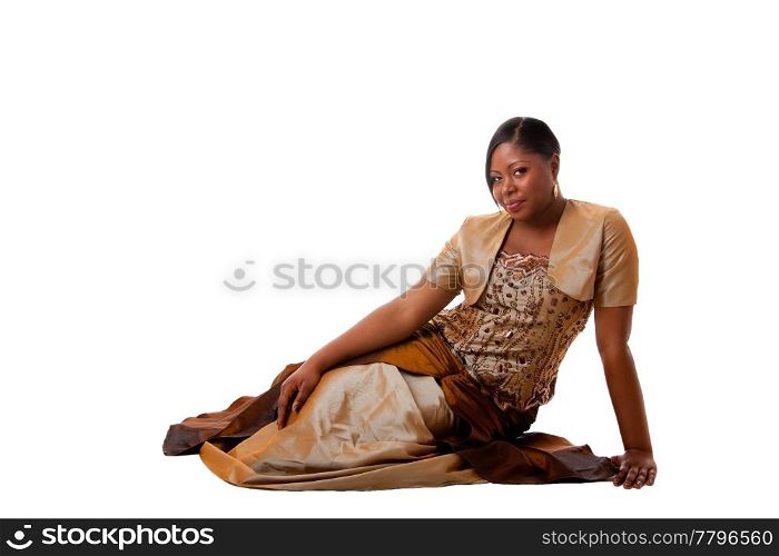 Beautiful African American woman in brown with gold dress, sitting laying on floor, isolated