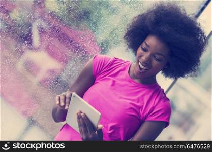 beautiful african american woman using tablet computer from home while rain and bad weather is outdoor. african american woman using tablet