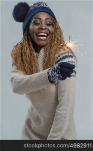 Beautiful african winter woman holding sparkler on gray background