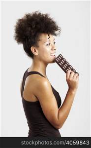 Beautiful african woman holding and eating a huge dark chocolate bar