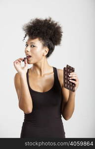 Beautiful african woman holding and eating a huge dark chocolate bar