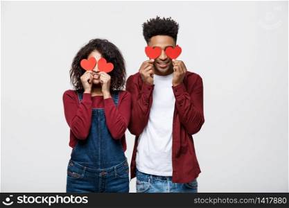 Beautiful Afro African American couple is holding red paper hearts and smiling, on gray background.. Beautiful Afro African American couple is holding red paper hearts and smiling, on gray background
