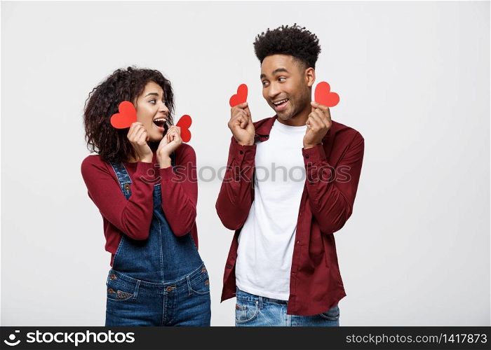Beautiful Afro American couple holding two red paper heart, looking at camera and smiling, isolated on white background.. Beautiful Afro American couple holding two red paper heart, looking at camera and smiling, isolated on white background