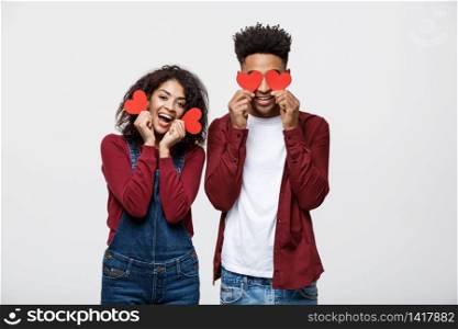 Beautiful Afro American couple holding two red paper heart, looking at camera and smiling, isolated on white background.. Beautiful Afro American couple holding two red paper heart, looking at camera and smiling, isolated on white background