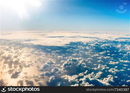 Beautiful airview with blue sky, white fluffy clouds and bright sunrays above them. Can be used as natural background