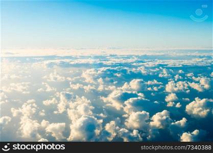 Beautiful airview with blue sky, white fluffy clouds and bright sunrays above them. Can be used as natural background