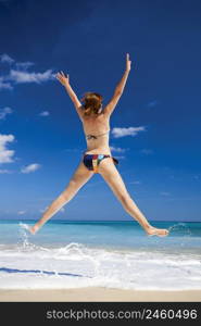 Beautiful and athletic young woman enjoying the summer, jumping in a tropical beach