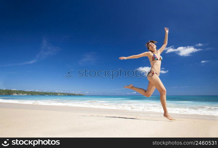 Beautiful and athletic young woman enjoying the summer, jumping in a tropical beach