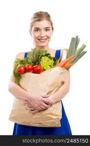 Beautiful and attractive woman carrying a bag full of vegetables, isolated over white background