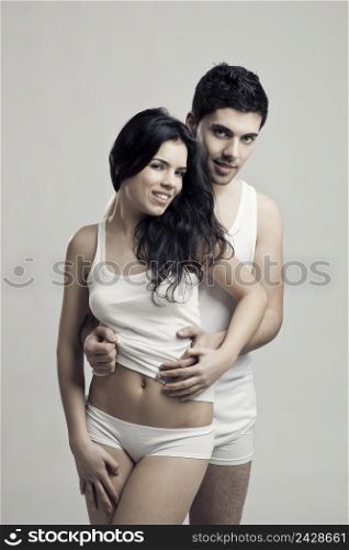 Beautiful and attractive young couple in underwear standing over a white background