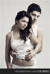 Beautiful and attractive young couple in underwear standing over a white background