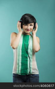 Beautiful and fashion woman listen music with headphones aganist a blue background