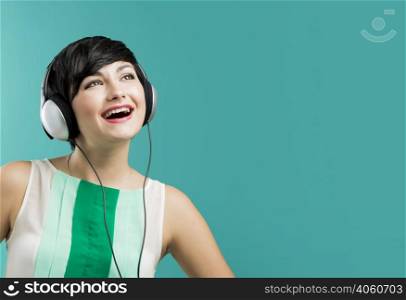 Beautiful and fashion woman listen music with headphones aganist a blue background
