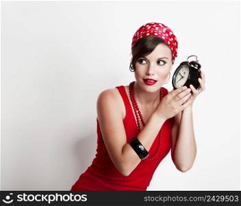Beautiful and fashion young woman with a pin-up look holding a clock