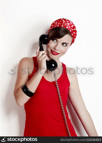 Beautiful and fashion young woman with a pin-up look. posing with a vintage phone