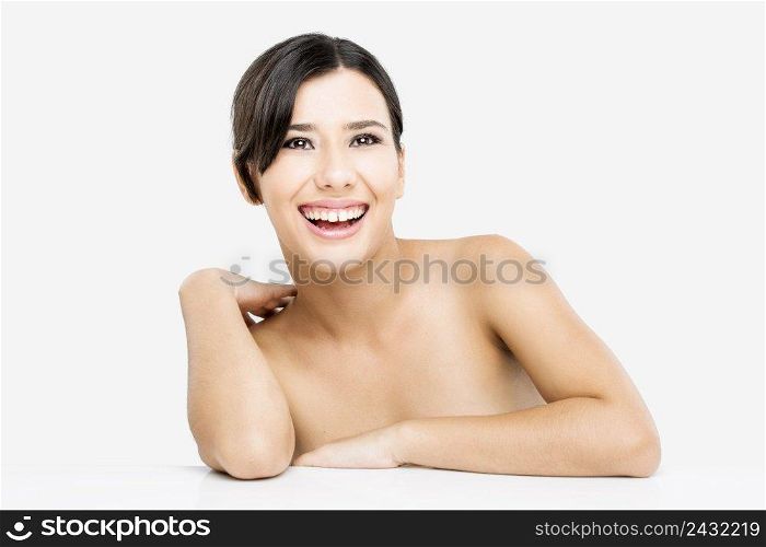 Beautiful and happy asian woman with arms over a white table