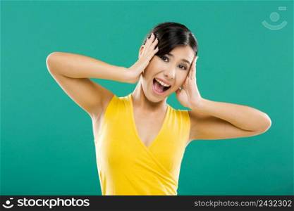 Beautiful and happy asian woman with hands on the face, over a green background