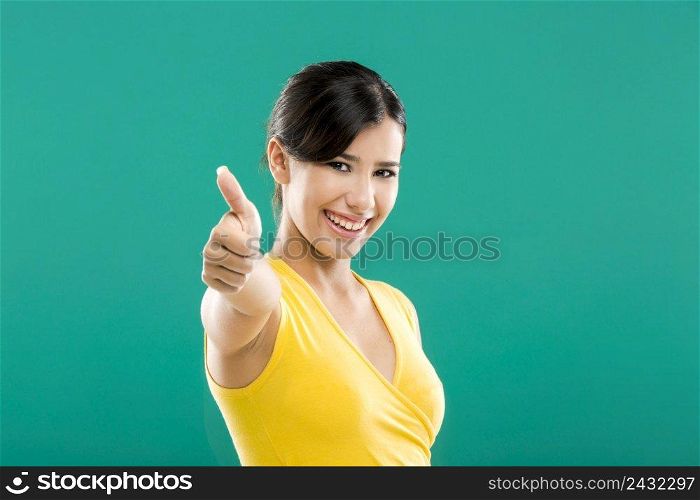 Beautiful and happy asian woman with thumbs up, over a green background