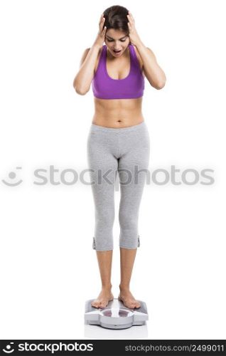 Beautiful and happy athletic woman over a scale with arms in the head, isolated on white background