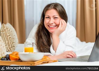 beautiful and happy girl on the bed with a tray of food