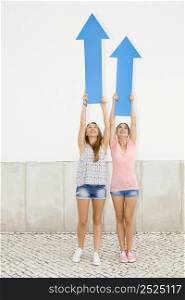 Beautiful and happy teenagers pointing blue arrows to the sky