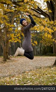 Beautiful and happy woman jumping in a autumn day
