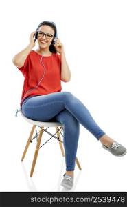 Beautiful and happy woman sitting on a chair and listen music, isolated over white background