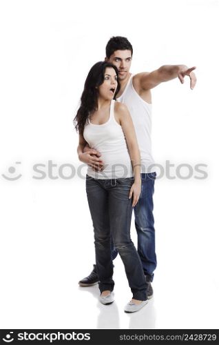 Beautiful and happy young couple pointing and astonish with something, standing over a white background
