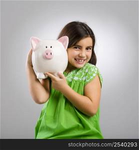 Beautiful and happy young girl holding a piggybank