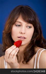 Beautiful and happy young woman eating a strawberry