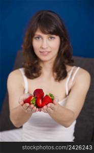 Beautiful and happy young woman holding strawberries with both hands