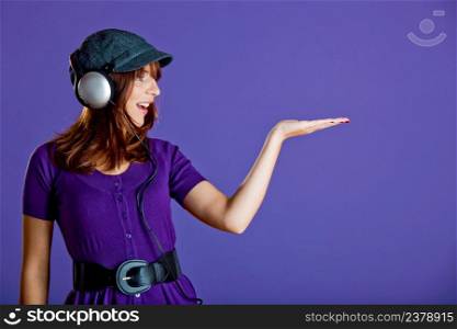 Beautiful and happy young woman listen music with headphones and looking to her hand