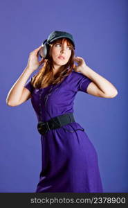 Beautiful and happy young woman listen music with headphones, over a violet background