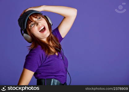 Beautiful and happy young woman listen music with headphones, over a violet background