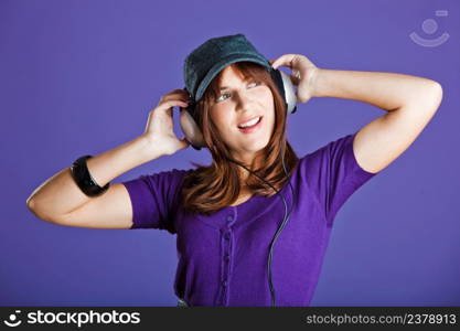 Beautiful and happy young woman listen music with headphones, over a violet background