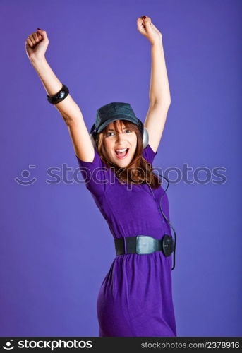 Beautiful and happy young woman listen music with headphones, over a violet background