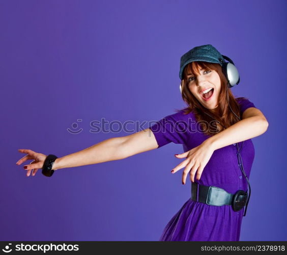 Beautiful and happy young woman listen music with headphones, over a violet background