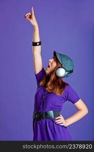 Beautiful and happy young woman listen music with headphones, over a violet background