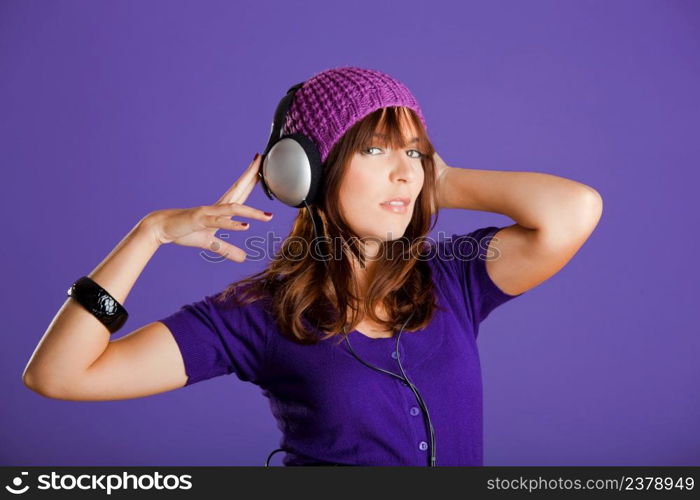 Beautiful and happy young woman listen music with headphones, over a violet background