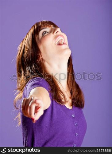 Beautiful and happy young woman pointing to you, over a violete background