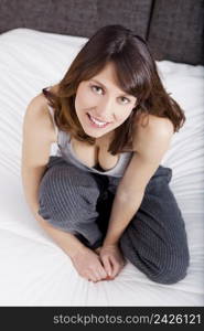 Beautiful and happy young woman sitting on the bed