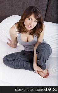 Beautiful and happy young woman sitting on the bed